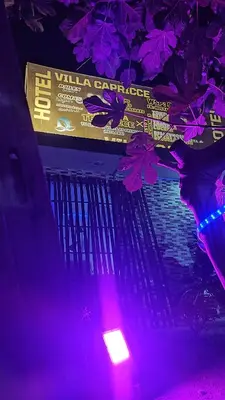 a sign hanging from a tree with purple lights at Hotel Villa Capricce in Puente Piedra