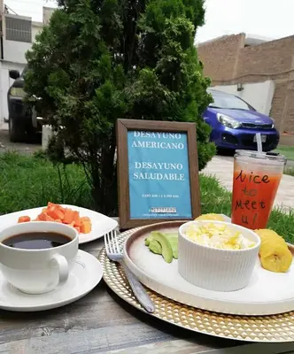 a table with two plates of food and a cup of coffee at Hotel Villa Capricce in Puente Piedra