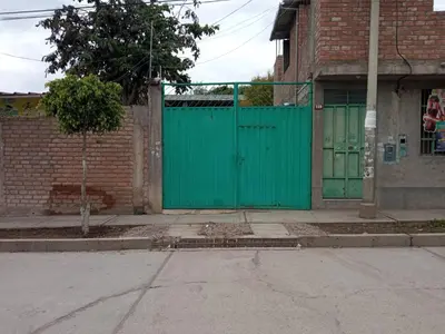 a green gate on the side of a brick building at Casa Hospedaje in Ayacucho