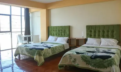 a hotel room with two beds and a window at Yanachaga Hotel - Oxapampa in Oxapampa
