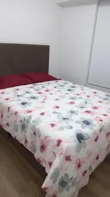 a bed with a flowered comforter with flowers on it at Lovely & quiet place, park view & private parking in Lima
