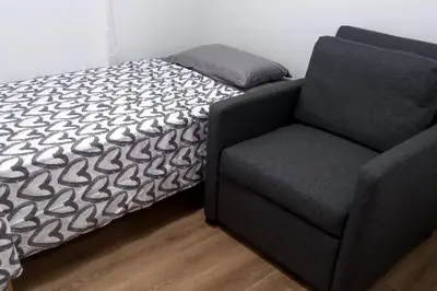 a bed and a chair in a room at Lovely & quiet place, park view & private parking in Lima