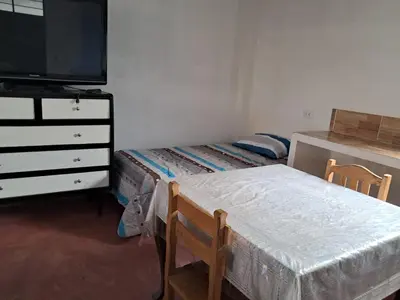 a bedroom with two beds and a dresser and a tv at Casa de Campo y Hospedaje Irma in Lunahuaná