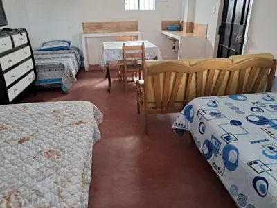 a bedroom with two beds and a table with a chair at Casa de Campo y Hospedaje Irma in Lunahuaná