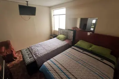 a bedroom with two beds and a mirror at Depawanka 3 Departamento amoblado y equipada in Huancayo