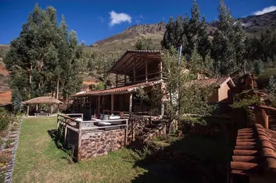 a house in a field with a mountain in the background at SAMAY WASI Rest house in Ollantaytambo
