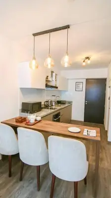 a kitchen with a wooden table and white chairs at Moderno Loft a Pasos del Centro in Cusco