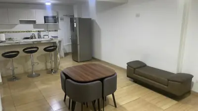 a kitchen with a table and a couch in a room at Acogedor departamento en Los Olivos 3 dormitorios in Lima