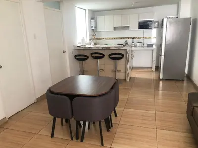 a kitchen with a wooden table and a refrigerator at Acogedor departamento en Los Olivos 3 dormitorios in Lima