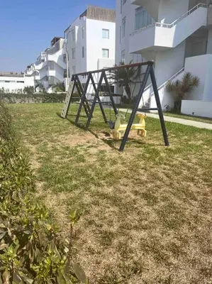 a swing set sitting in the grass near a building at Casa de Playa muy cerca al mar, piscina exclusiva! in Islote Los Leones