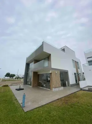 a large white building in a field of grass at Casa de Playa muy cerca al mar, piscina exclusiva! in Islote Los Leones