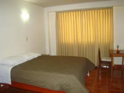 a bedroom with a bed and a desk and a window at Kibo Hotel in Ayacucho