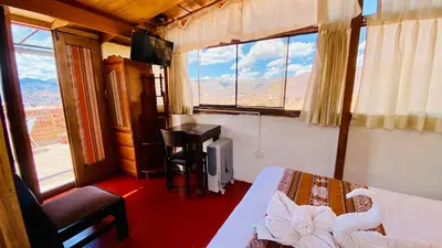 a bedroom with a bed and a desk and windows at Amira's House Cusco in Cusco