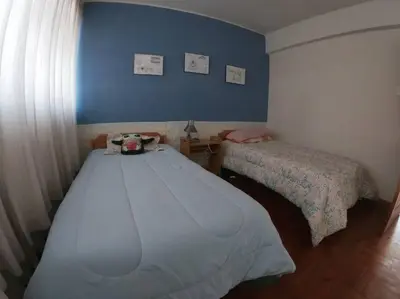 a bedroom with two beds and a blue wall at Departamento céntrico en Cusco in Cusco