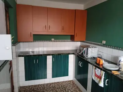 a kitchen with green and brown cabinets and a counter at Departamento céntrico en Cusco in Cusco