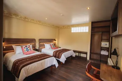 a hotel room with two beds and a table at Valle Del Sol in Urubamba
