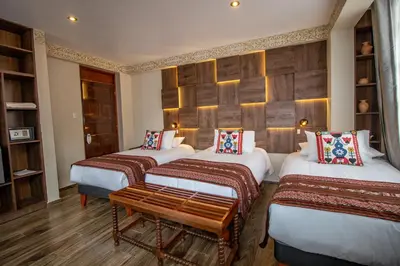 a room with three beds and a bench in it at Valle Del Sol in Urubamba