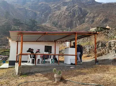 a group of people sitting at a table in a shed at Casa de campo con impresionante vista a las montañas y cascada en Canta in Canta