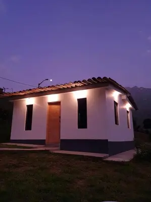 a small white house with lights on top of it at Casa de campo con impresionante vista a las montañas y cascada en Canta in Canta