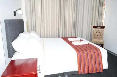 a hotel room with a white bed and a chair at Hotel Santa Felicita - Centro Histórico in Huancayo