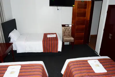 a hotel room with two beds and a chair at Hotel Santa Felicita - Centro Histórico in Huancayo