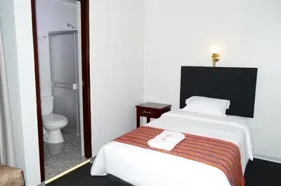 a bedroom with a bed and a bathroom with a toilet at Hotel Santa Felicita - Centro Histórico in Huancayo