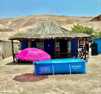 a small building with a pink umbrella in the desert at Bungalows frente al mar en playa Wakama in San Vicente de Cañete