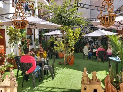 a group of people sitting at tables in a garden at Hotel SumacPlaza in Ayacucho