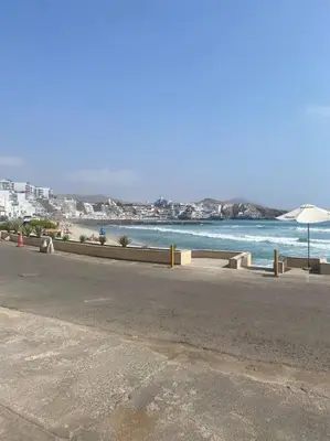 an empty street next to a beach with an umbrella at Alojamiento frente al mar en San Bartolo in San Bartolo