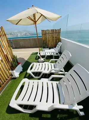 three lounge chairs and an umbrella on a balcony at Alojamiento frente al mar en San Bartolo in San Bartolo