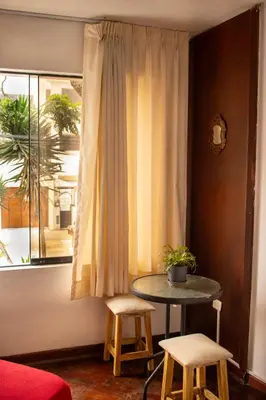 a table and two stools in a room with a window at Temazcal Hostel in Lima