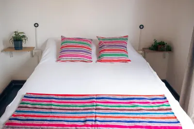 a white bed with two colorful pillows on it at Temazcal Hostel in Lima