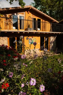 a house with a balcony and flowers in the yard at Casa Tikawarmi in Urubamba
