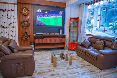 a living room with two leather couches and a tv at Chakana Hotel Machupicchu in Machu Picchu