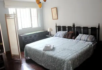 a bedroom with a large bed with a blue comforter at Palmeras Apartments San Isidro in Lima