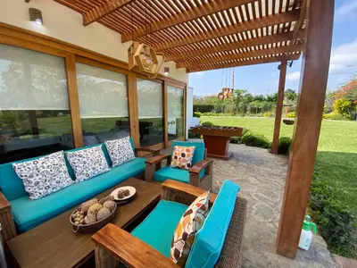 a patio with a blue couch and chairs under a wooden pergola at Casa de campo en Hacienda San Andres in San Andrés