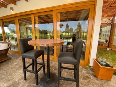 a wooden table and chairs in a room with windows at Casa de campo en Hacienda San Andres in San Andrés