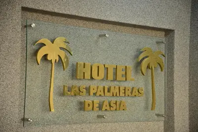 a hotel sign with two palm trees on a wall at Qallwa Asia in Asia
