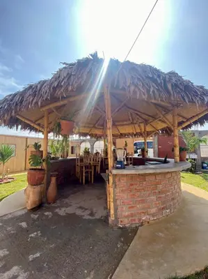 a bar with a straw umbrella on top of a brick wall at Coco y Ainhoa Lodge in Paracas