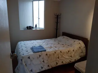 a bedroom with a bed with a white comforter and a window at Benito in Lima
