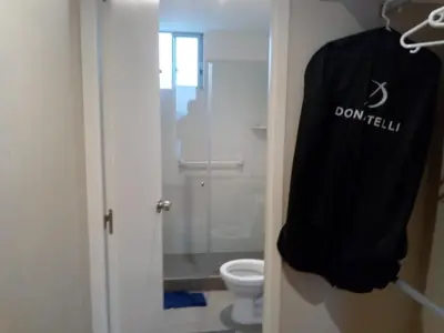 a bathroom with a toilet and a robe hanging on the door at Benito in Lima