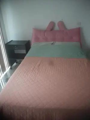 a bedroom with a bed with a red comforter and a table at Microdepartamento amoblado in Lima