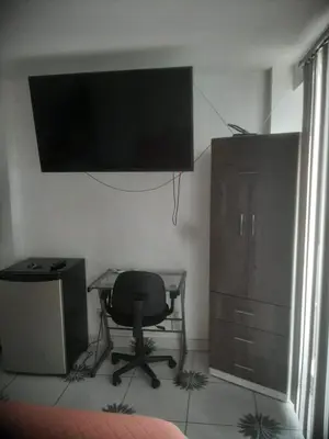 a bedroom with a desk and a chair and a television at Microdepartamento amoblado in Lima