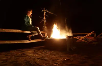 a man sitting on a bench next to a fire at SAMAY WASI Rest house in Ollantaytambo