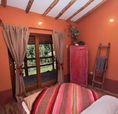 a bedroom with orange walls and a bed with a window at SAMAY WASI Rest house in Ollantaytambo