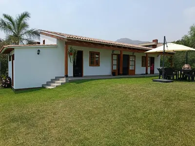 a small white house with a grass yard at Casa pachacamac in Pachacamac