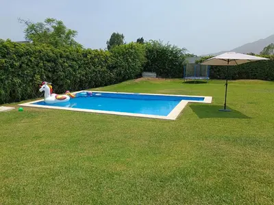 a swimming pool in a yard with an umbrella at Casa pachacamac in Pachacamac