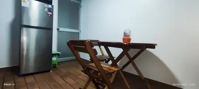 a wooden table with a wooden chair next to a refrigerator at Posada Estela in Lima