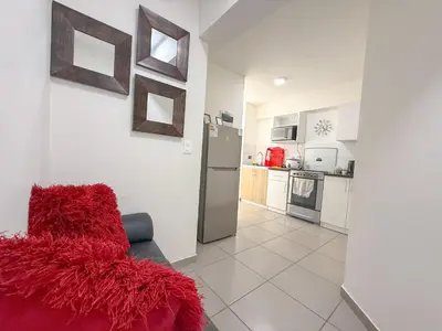 a living room with a red couch and a kitchen at Exclusivo con vista al mar - Blue One in Lima