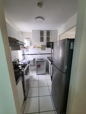a kitchen with a stainless steel refrigerator and white cabinets at Departamento Centenario in Lima